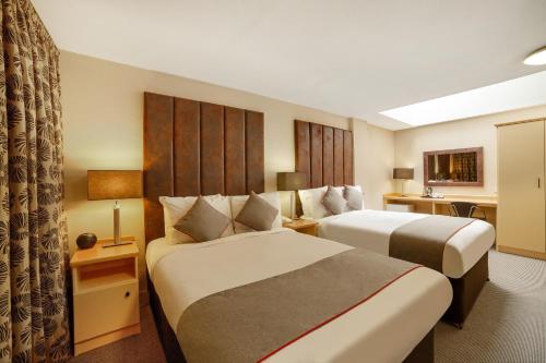 a hotel room with two beds and a desk at Highland Aberdeen City Centre in Aberdeen