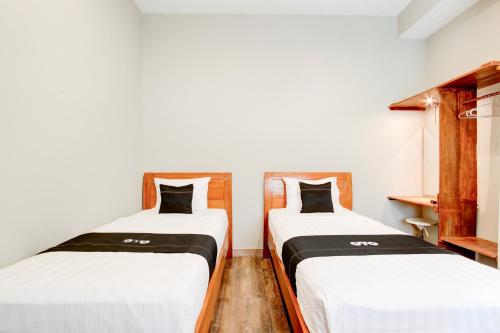 two beds in a room with white and black sheets at Capital O 94274 Homestay Balimoelih in Yogyakarta