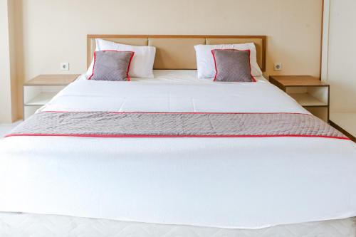 a bedroom with a large white bed with two pillows at Collection O Serviced Apartmen Mutiara Kota in Bekasi