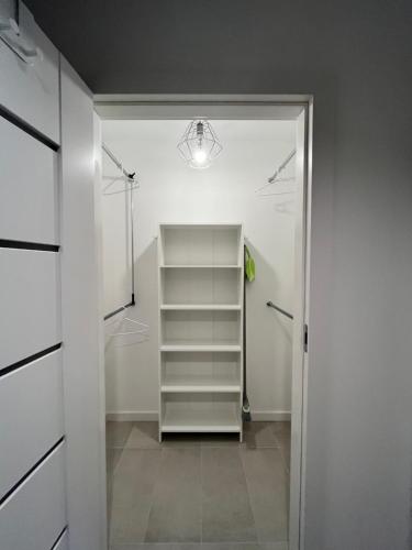 a walk in closet with a shelf and a light at Apartament Julia 1-4 os Starowapiennikowa 42a z balkonem, klimatyzacją i miejscem parkingowym in Kielce