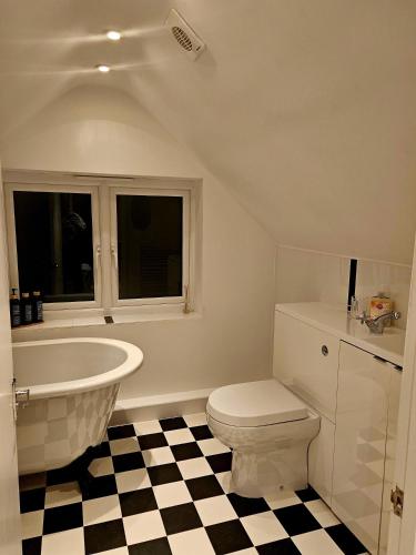 a bathroom with a tub and a toilet and a sink at The Glen in Hythe