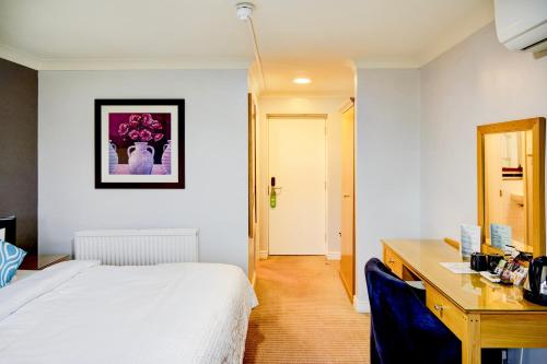 a bedroom with a white bed and a desk with a desk at Warwickshire Park Hotel Kenilworth by Belvilla in Kenilworth
