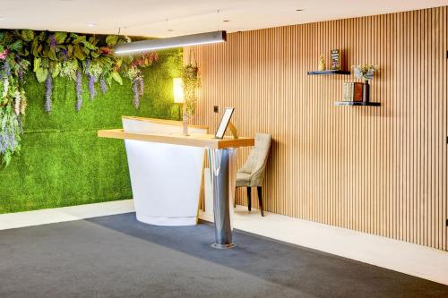 a reception desk in a room with a green wall at Warwickshire Park Hotel Kenilworth by Belvilla in Kenilworth