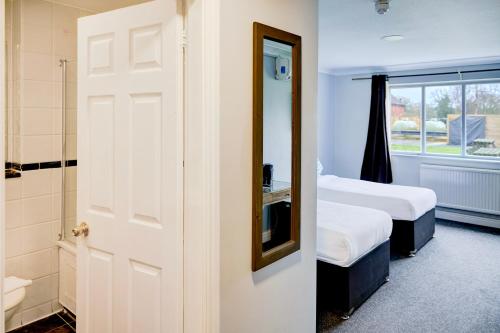 a room with two beds and a bathroom with a mirror at Warwickshire Park Hotel Kenilworth by Belvilla in Kenilworth