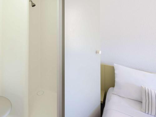 a bedroom with a bed and a white wall at ibis Budget - Campbelltown in Campbelltown
