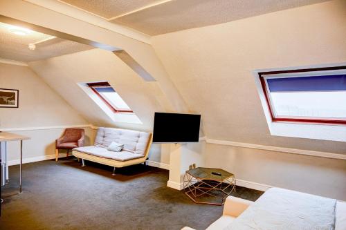 a attic room with a couch and a tv at Warwickshire Park Hotel Kenilworth by Belvilla in Kenilworth