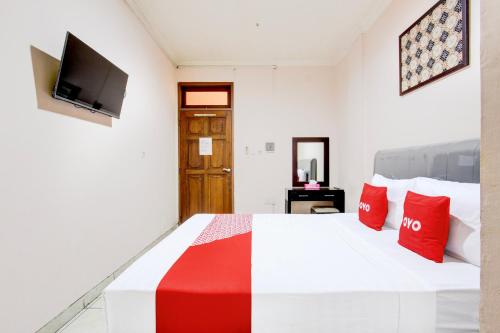 a bedroom with a bed with red pillows and a tv at Collection O Simpang Lima Near Simpang Lima Semarang Formerly Hotel Eben Haezer in Semarang