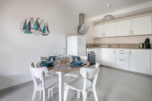 une cuisine avec une table et des chaises et une cuisine avec des armoires blanches dans l'établissement Appartement à 150m de la Mer - 4 personnes, à Pornic