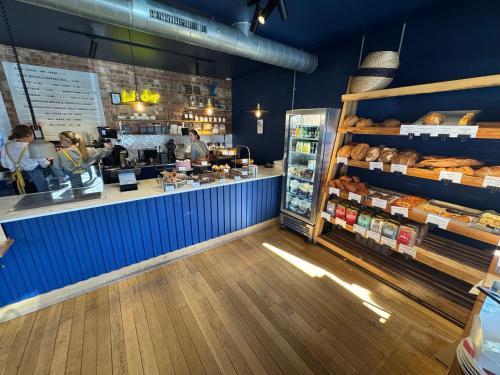 a bakery with a counter with breads and a customer at Charming one bedroom cottage in Basingstoke