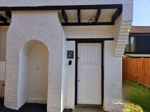 a white brick house with a white door and an arch at The Grieg in Wadhurst