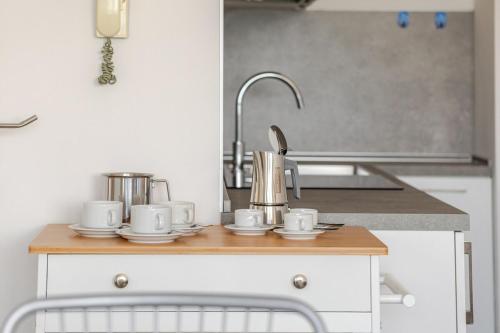 a kitchen counter with cups and saucers on it at La Terrazza sul Mare with parking in Lignano Sabbiadoro