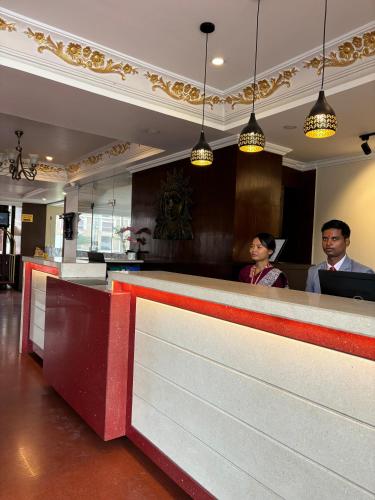 two people standing at a counter in a restaurant at Palette 823 Hotel Ichchha in Simara