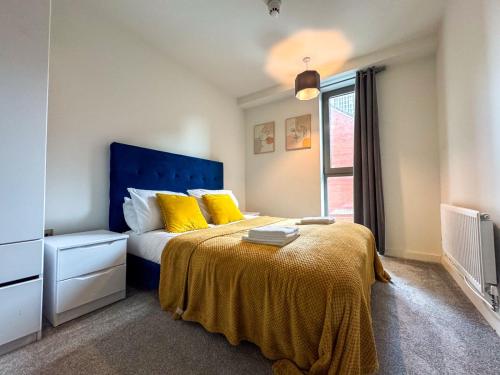 1 dormitorio con 1 cama con cabecero azul y almohadas amarillas en M1 Townhouse - Free Parking & Central Manchester, en Mánchester