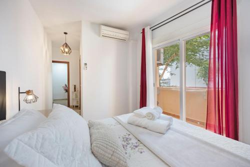 sypialnia z białym łóżkiem i oknem w obiekcie Apartamento Los Jardines w mieście El Puerto de Santa María