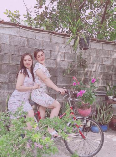 two girls sitting on a bike next to a brick wall at Khang Bảo Viên in Củ Chi