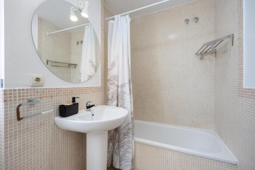 łazienka z umywalką, wanną i lustrem w obiekcie Apartamento Los Jardines w mieście El Puerto de Santa María