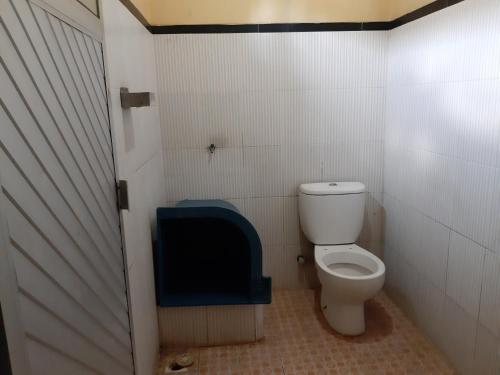 a bathroom with a toilet with a blue door at Hotel O Houstel Darma Syariah in Probolinggo
