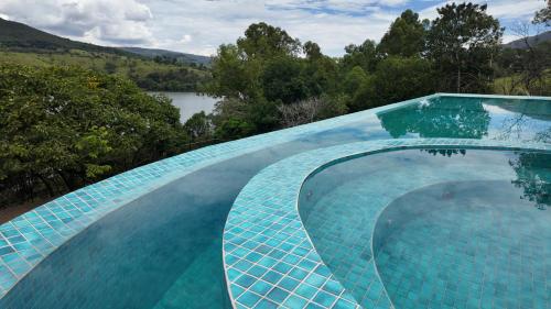 a blue tile swimming pool with a view of a lake at Collegare Hotel in Capitólio