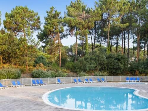 - une piscine avec des chaises longues bleues et des arbres dans l'établissement Séjour Piscine, Forêt, Océan à Soustons Plage, à Soustons