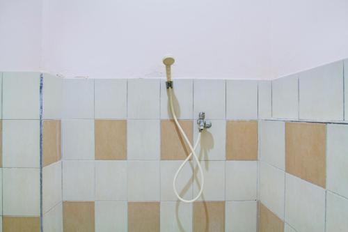 a shower with a hose in a tiled bathroom at Collection O Simpang Lima Near Simpang Lima Semarang Formerly Hotel Eben Haezer in Semarang