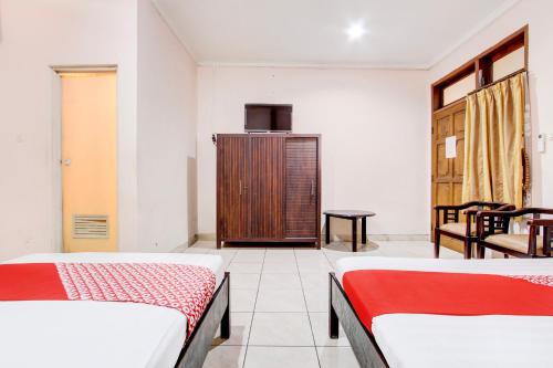 a room with two beds and a wooden cabinet at Collection O Simpang Lima Near Simpang Lima Semarang Formerly Hotel Eben Haezer in Semarang