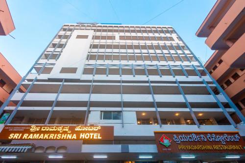 a tall white building with a sign in front of it at Sri Ramakrishna Hotel in Bangalore