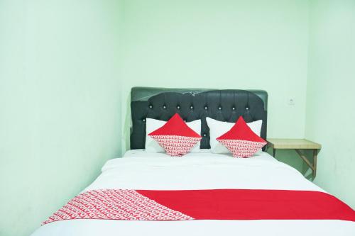 a bed with red and white pillows on it at Hotel O Ilir Timur I Near Rsud Siti Fatimah Az-Zahra Formerly Lumendiva Suite in Palembang