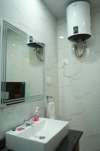 a white bathroom with a sink and a mirror at Hotel Golden Palace in Lucknow