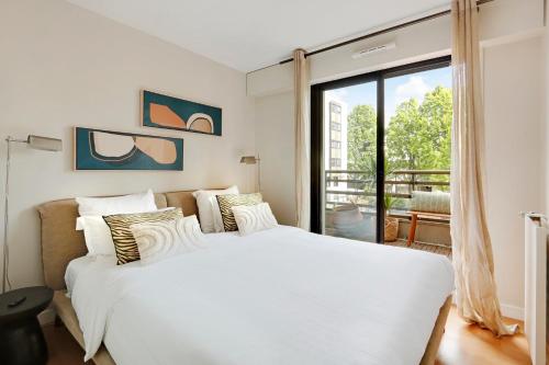 une chambre avec un lit blanc et une grande fenêtre dans l'établissement Spacieux 2 pièces rénové avec terrasse et parking proche La Défense, à Levallois-Perret