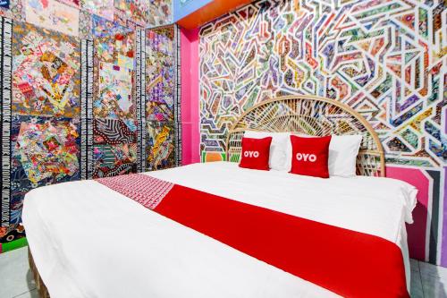 a bed with two red pillows in front of a colorful wall at Hotel O Seturan Near Ugm Formerly Palem Kecut in Sleman