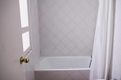 a white bath tub with a window and a shower curtain at Calafate 4 in L'Ametlla de Mar
