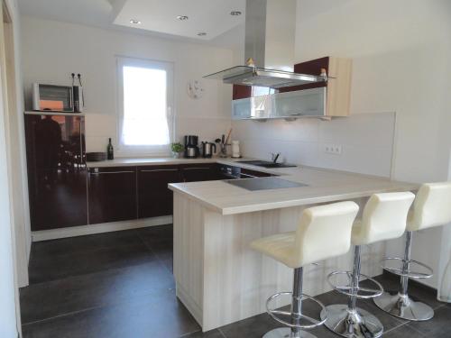 une cuisine avec un comptoir avec des chaises blanches à l'intérieur dans l'établissement Haus Lütti, à Glowe