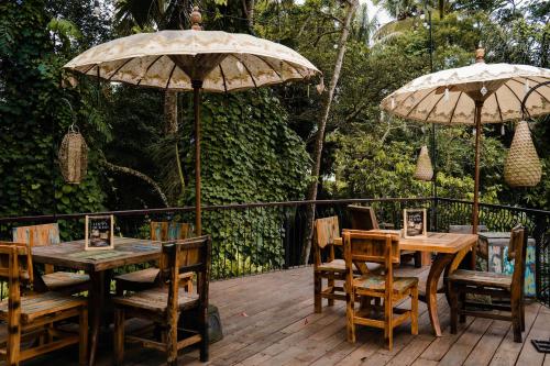 two tables and chairs with umbrellas on a deck at Vije Boutique Resort & Spa in Ubud
