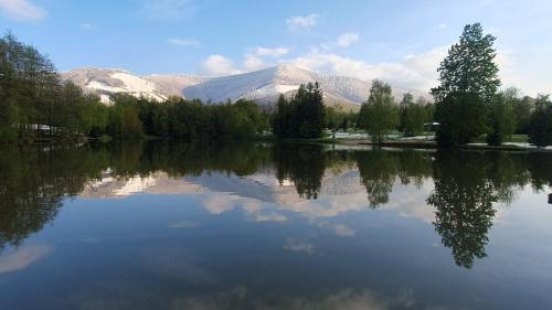 a large lake with mountains in the background at Radhošťský rybník in Trojanovice