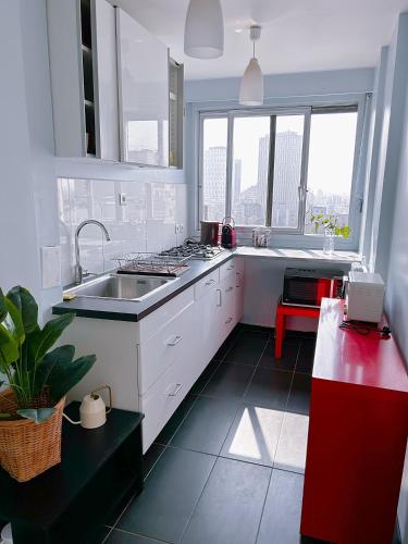 une cuisine avec des placards blancs et une grande fenêtre dans l'établissement Large charming studio in Paris, à Paris
