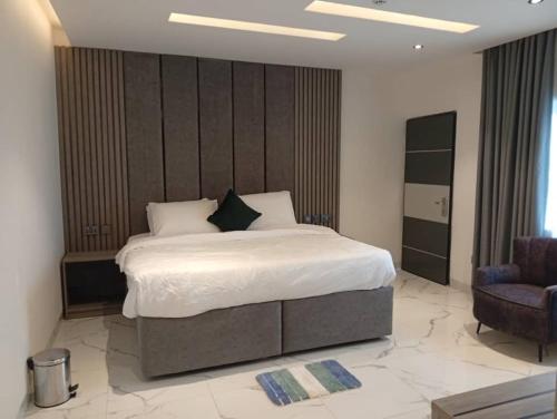 a bedroom with a large bed and a chair at Calico Hotel and Suites, Abuja in Gwarinpa