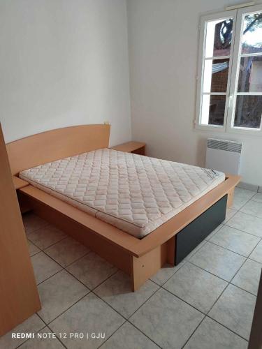 - un lit en bois dans une chambre avec fenêtre dans l'établissement Maison Familiale à Deux Pas de la Mer, à Saint-Brévin-lʼOcéan