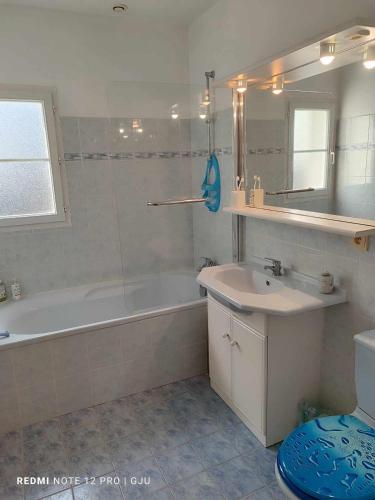 une salle de bain avec une baignoire, un lavabo et un miroir dans l'établissement Maison Familiale à Deux Pas de la Mer, à Saint-Brévin-lʼOcéan