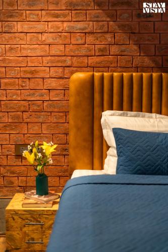 a bedroom with a blue bed and a brick wall at StayVista at Frozen Fall at Dewdrop Cottages with BBQ & Bonfire in Gulmarg