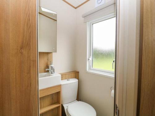 a bathroom with a toilet and a sink and a window at 75 Foxburrow Hang in Great Yarmouth