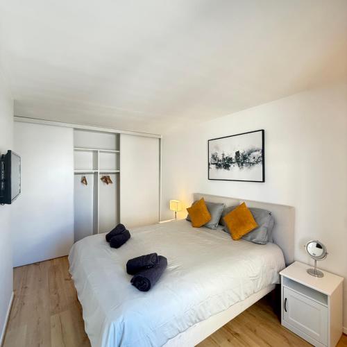une chambre avec un grand lit blanc avec des oreillers orange dans l'établissement Appartement moderne au centre-ville de Villeneuve La Garenne, à Villeneuve-la-Garenne