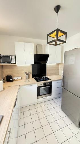 une cuisine avec des armoires blanches et un four à plaques de cuisson dans l'établissement Appartement moderne au centre-ville de Villeneuve La Garenne, à Villeneuve-la-Garenne