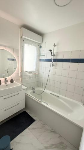 une salle de bain blanche avec une baignoire et un lavabo dans l'établissement Appartement moderne au centre-ville de Villeneuve La Garenne, à Villeneuve-la-Garenne