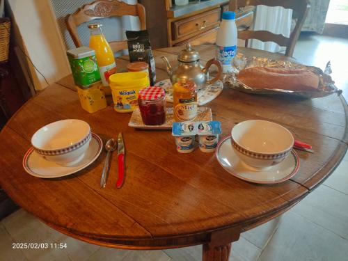 ein Holztisch mit zwei Tassen und Tellern darauf in der Unterkunft home edwige in Fresse