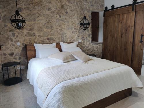 a bedroom with a white bed in a stone wall at Casa do Cruzeiro in Ourém