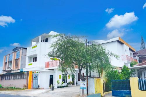 un edificio bianco con un albero di fronte di Hotel O Teluk Betung Near Water Park Lembah Hijau Formerly Kanajiwa Guesthouse 2 a Lampung