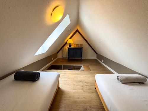 une chambre mansardée avec deux lits et une fenêtre dans l'établissement L'Harmonie des Combles - Proche Gare - Petite France - Commerces à proximité, à Strasbourg