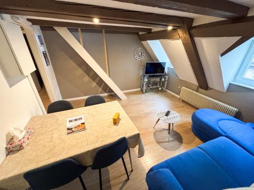 un salon avec une table et un canapé bleu dans l'établissement L'Harmonie des Combles - Proche Gare - Petite France - Commerces à proximité, à Strasbourg