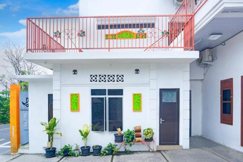una casa bianca con piante e balcone rosso di Hotel O Teluk Betung Near Water Park Lembah Hijau Formerly Kanajiwa Guesthouse 2 a Lampung