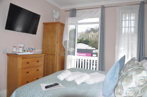a bedroom with a bed with a television and a window at Hotel Peppers in Torquay